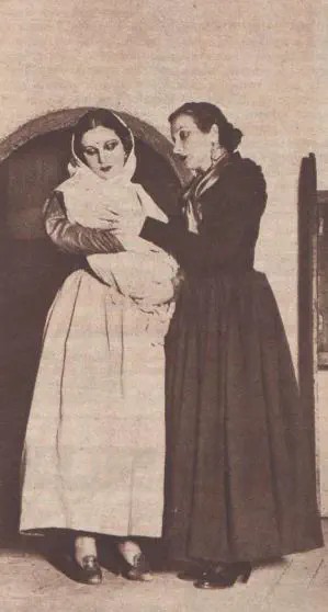 An old, sepia picture of two actresses on a stage. One dresses in white and is holding a baby, the other is dressed in black